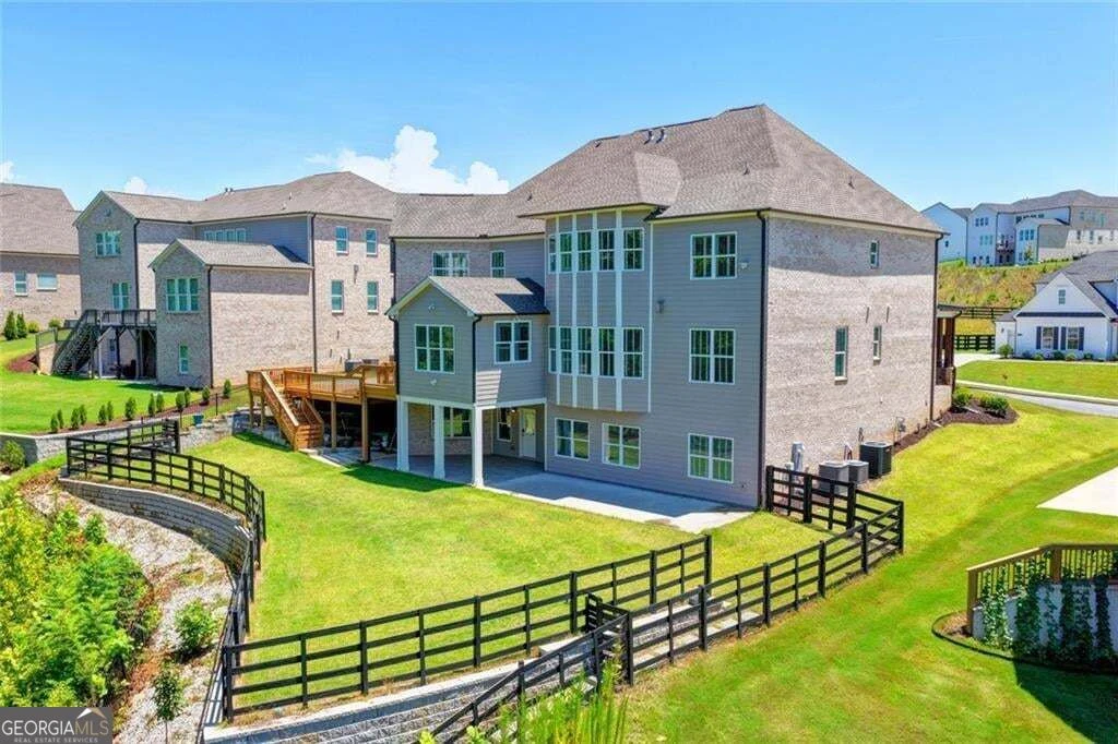 Rear of the home showing deck, lawn and fenced yard