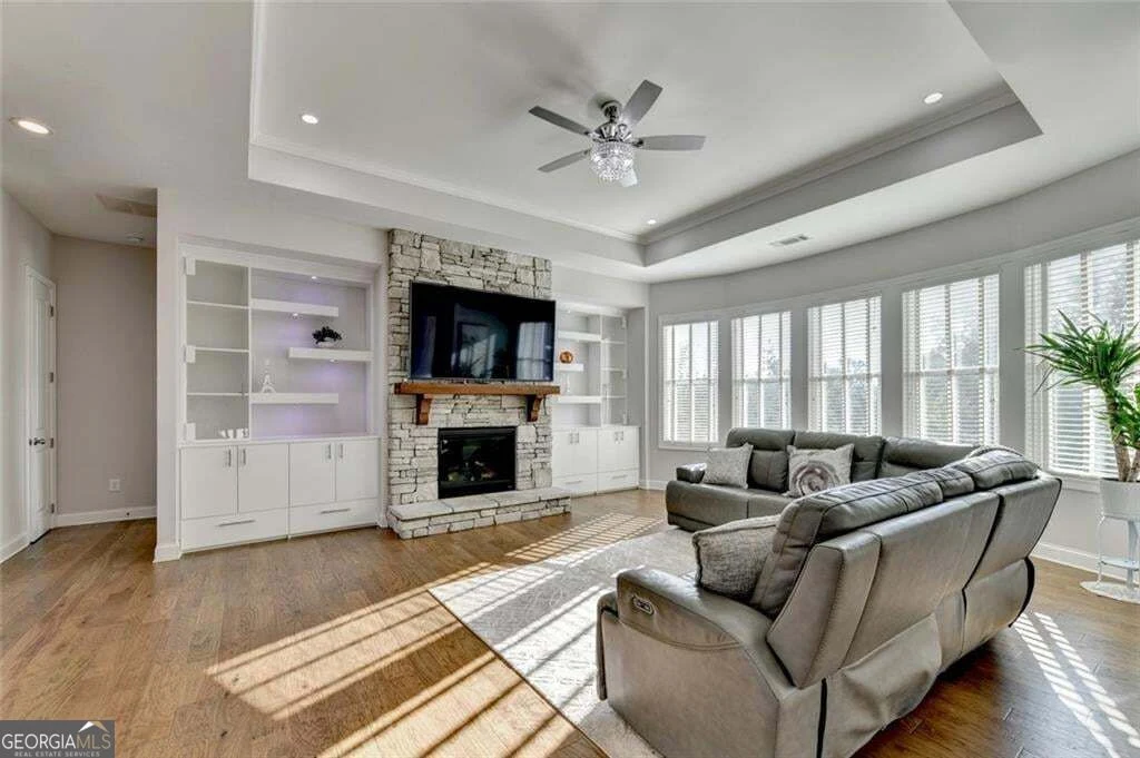 Sunlit great room with fireplace, built-in shelving and windows