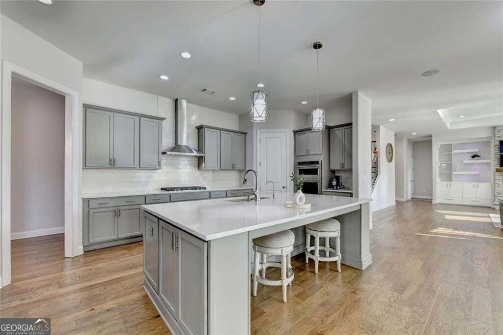 Main-level kitchen with white cabinetry, large island and pendant lights