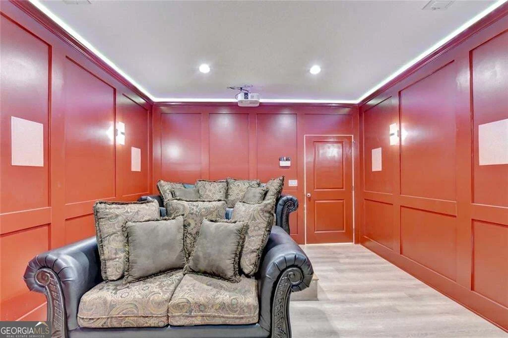 Theater room with deep red paneled walls and reclining seating